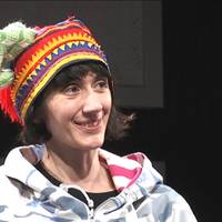 En tjej som har på sig en samisk mössa och håller på den med en grön vante.