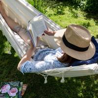 Kvinna läser i en hängmatta.