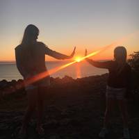 Två flickor "håller" solen i sin nedgång