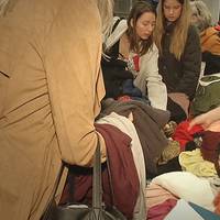 Personer letar i högar av kläder.