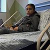 Amira ligger i sjukhussäng, hennes mamma sitter bredvid sängen.