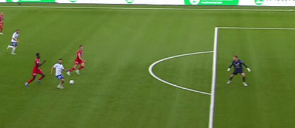 Anfallare närmar sig målvakten i ett friläge under en fotbollsmatch.