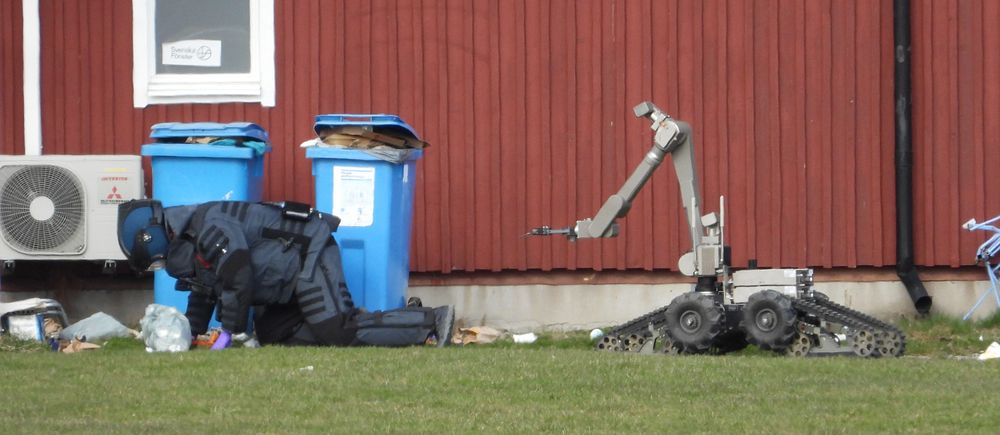 Bombtekniker och robot vid röda byggnaden.
