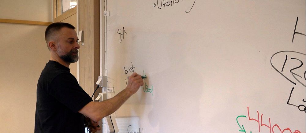 En man skriver på en whiteboard.