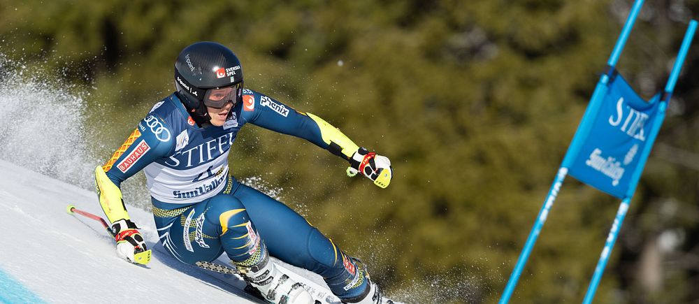 Sara Hector i blå dräkt åker ner för en backe med två stavar