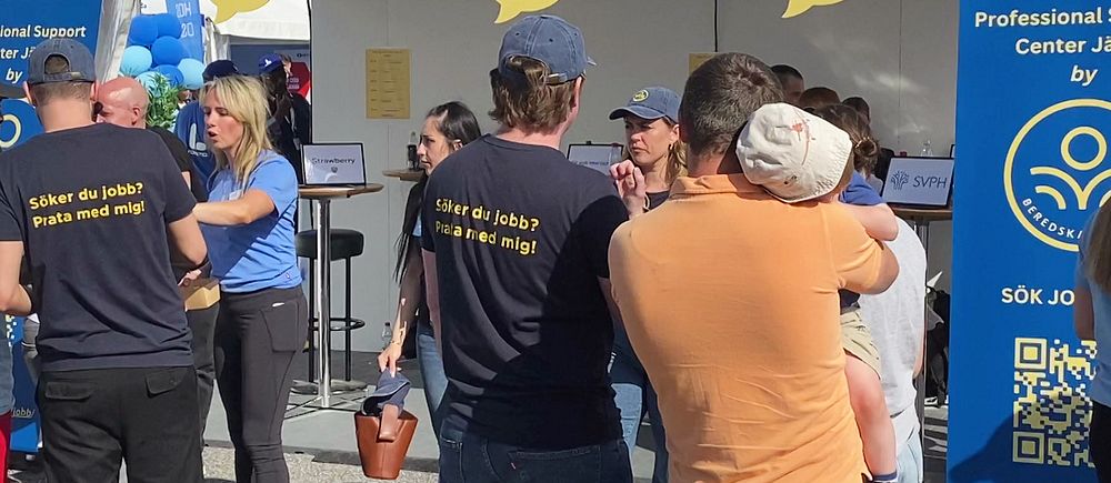 Personer med texten ”Söker du jobb? Prata med mig” på ryggen på t-shirt, framför tält för arbetssökande under Järvaveckan