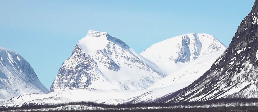 Vy över snötäckta fjäll iNnorra Lappland.