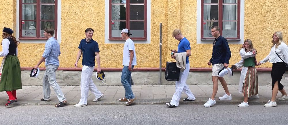 Studenter som går med ena foten på trottoaren och en på gatan