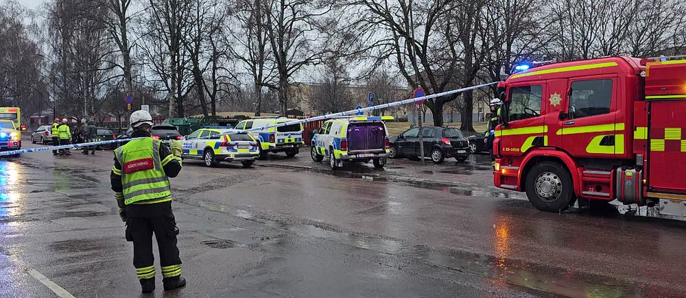 Brandbil och polisfordon har spärrat av ett område. En brandman står vid avspärrningen.