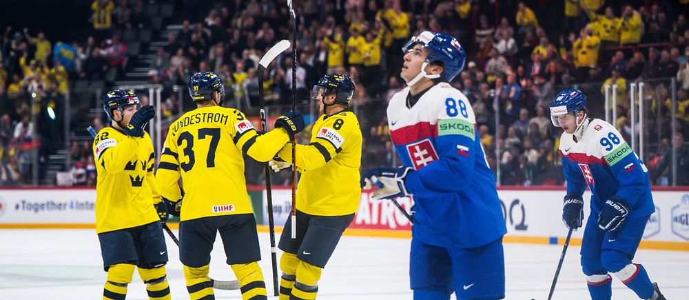 Svenska ishockeyspelare firar mål, slovakiska spelare besvikna i förgrunden.