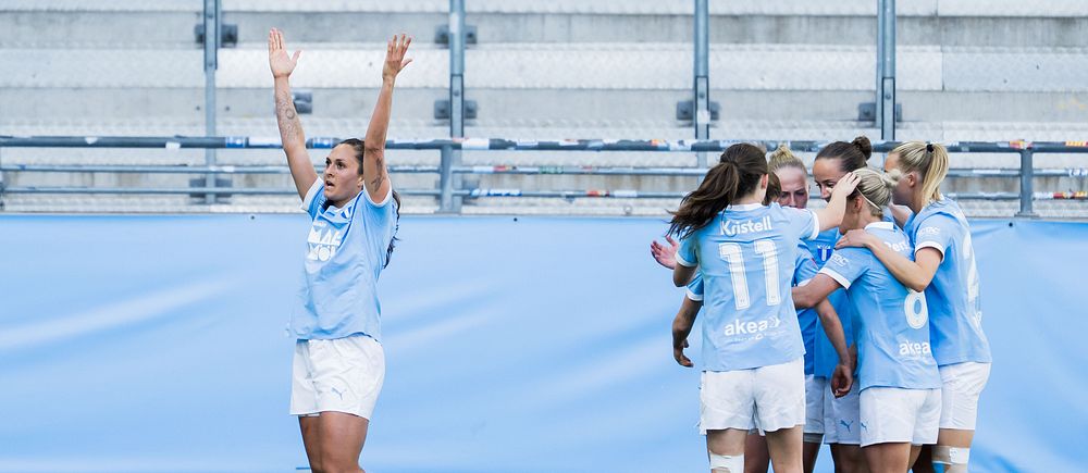 Fotbollsspelare i ljusblått firar mål, en spelare jublar med armarna i luften.