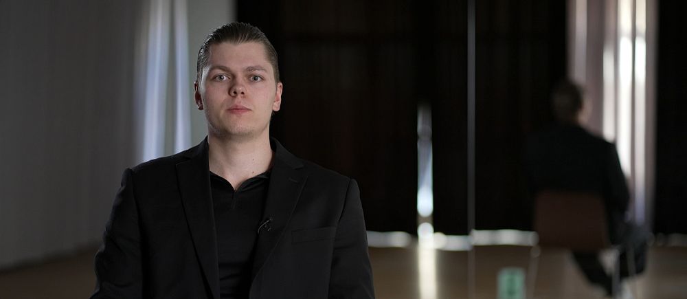 En person sittande i ett mörkt rum.