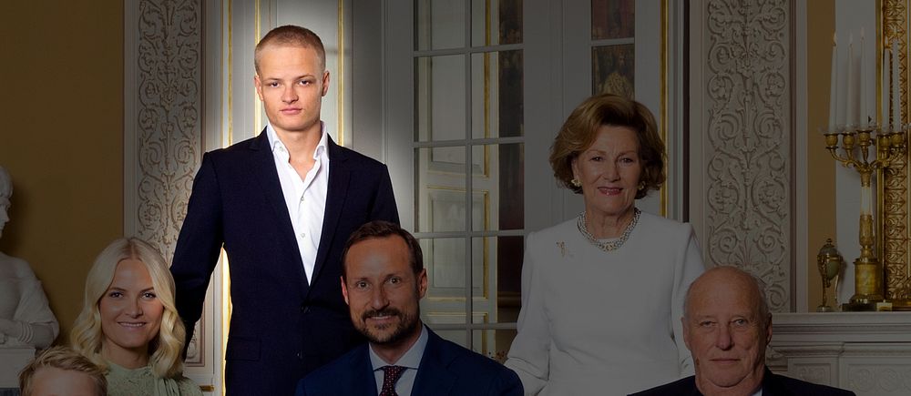 Gruppfoto av norska kungafamiljen klädda i formella kläder, samlade i en elegant inomhusmiljö med ljusa väggar och stiliga inredningsdetaljer. En person (Marius Borg Høiby) står i mitten.
