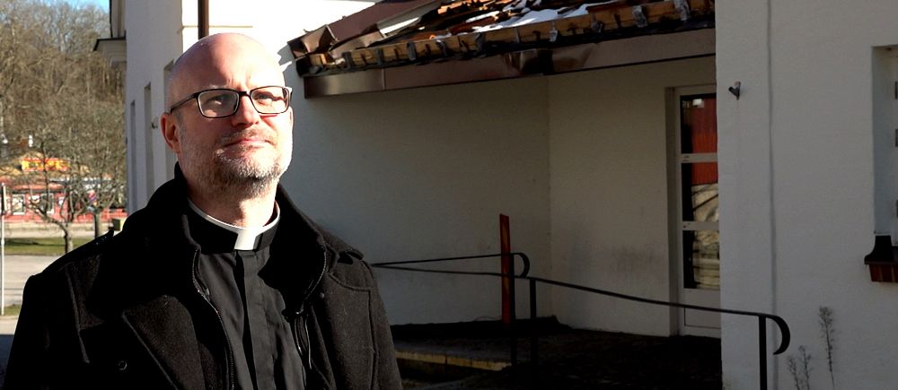 Patrik Ingemansson står i en prästkrage utanför Kyrkans Hus i Ronneby. Koppar har stulits från taket över entrén.