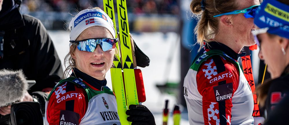 Skidåkare i tävlingsdräkt diskuterar med en reporter på vintersporttävling.