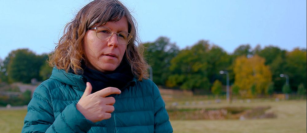 Kvinna i dunjacka pratar teckenspråk