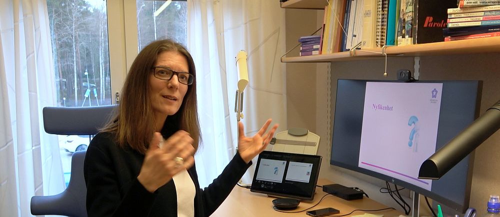 Céline Rocher Hahlin, står i sitt arbetsrum framför sin dator där hon håller sina distanslektioner.
