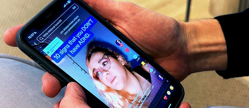 Person håller mobil, video om ADHD visas på Tiktok.
