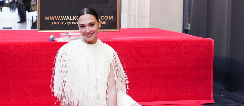 Person i vit klänning poserar vid en stjärna på Hollywood Walk of Fame.