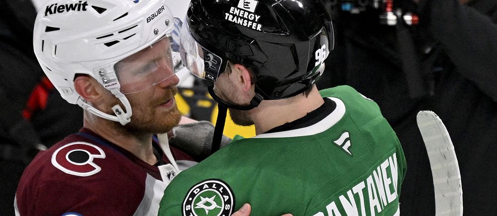 Två hockeyspelare från olika lag kramas efter matchen på isen.