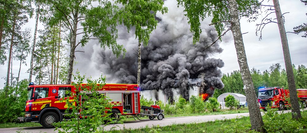 räddningstjänstens bil står framför ett stort moln av mörkgrå rök