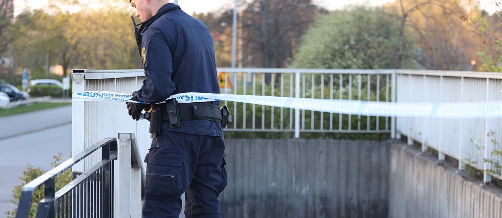 Polis sätter upp avspärrningsband vid en gångtunnel under en bro.