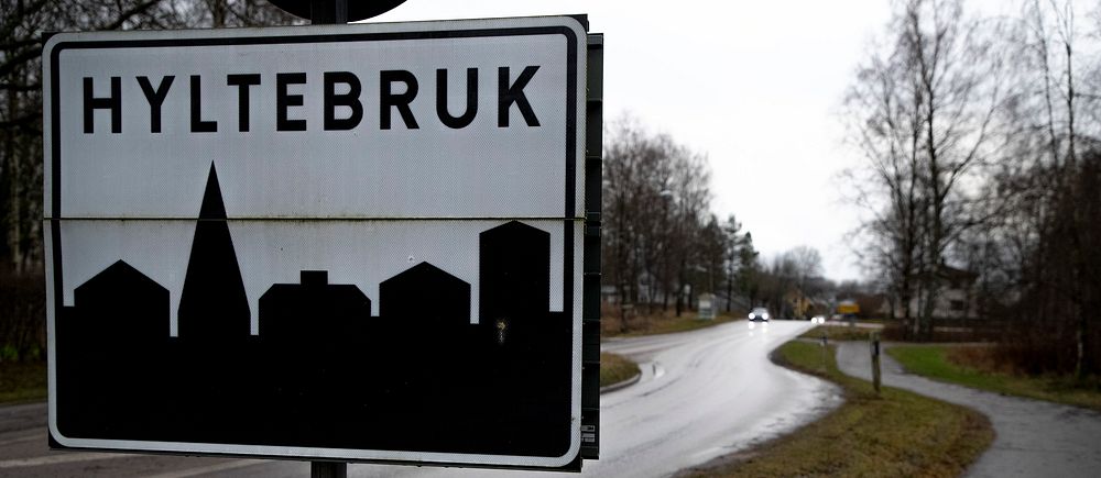 Vägskylt vid infart till Hyltebruk, omgivning med väg och träd.