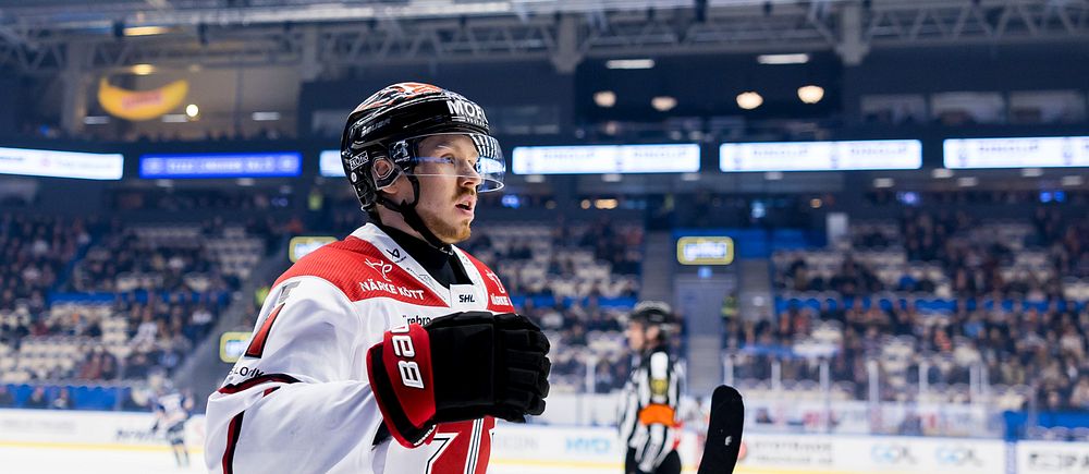 Ishockeyspelare går av isen under en match, publik syns i bakgrunden.