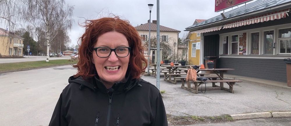 Person med rött hår står framför en gatukrog på en tom gata under mulen himmel.