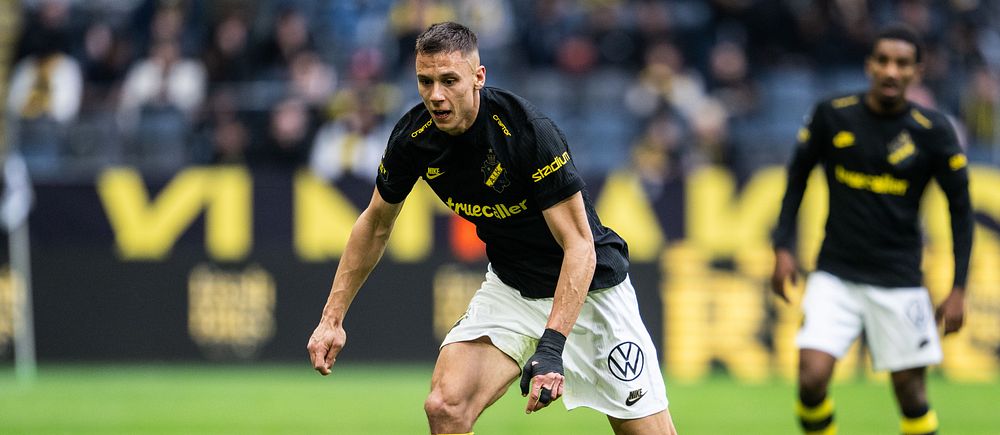 AIK-spelare springer med bollen på fotbollsplan under pågående match.