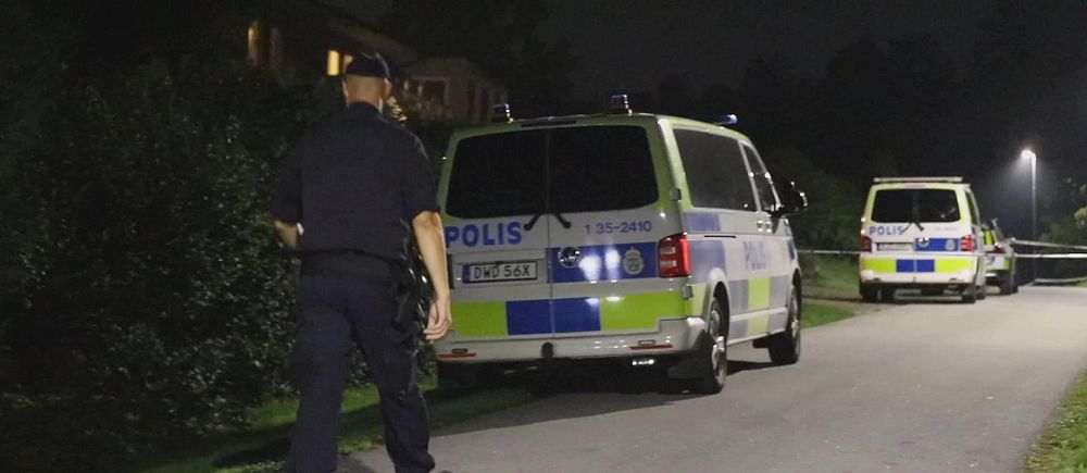 Polis går vid parkerade polisbilar