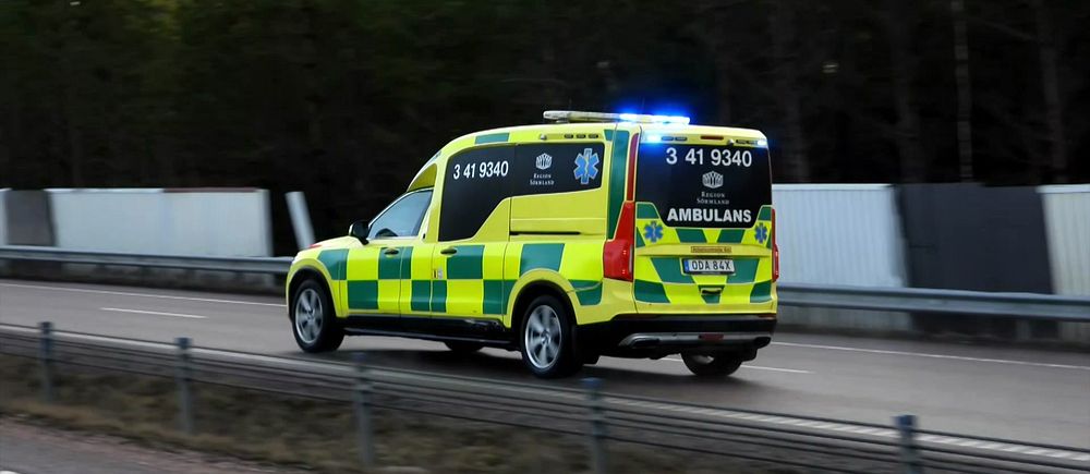 Ambulans med blåljus kör i hög hastighet på en landsväg.
