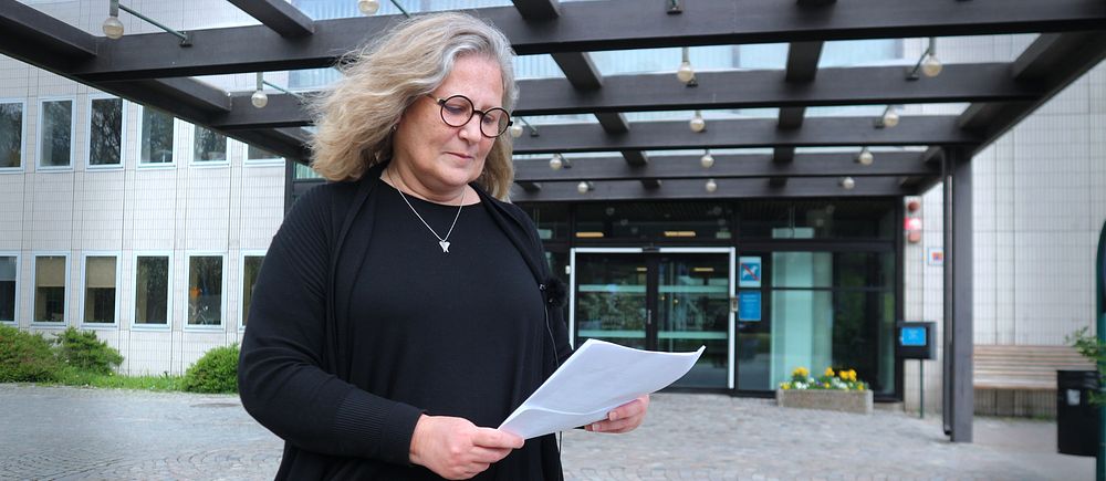 kvinna med papper i handen utanför Ronneby Stadshus