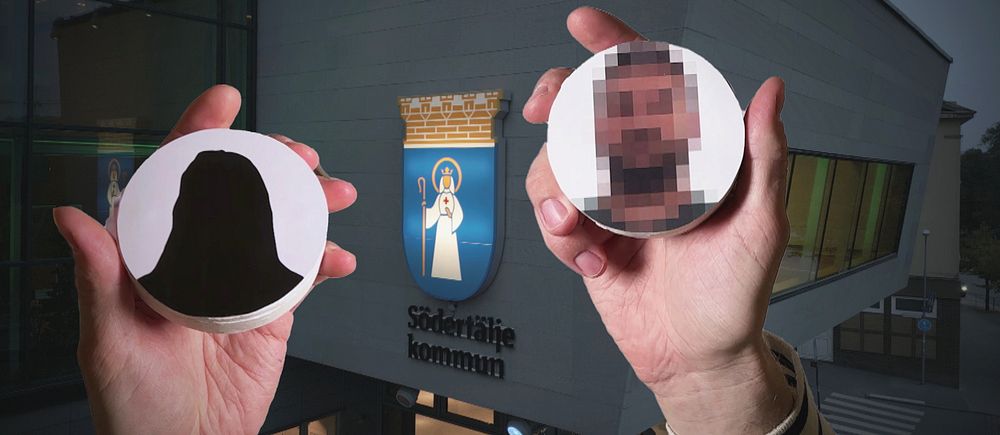 Två händer håller runda skyltar framför Södertäljes kommuns byggnad.