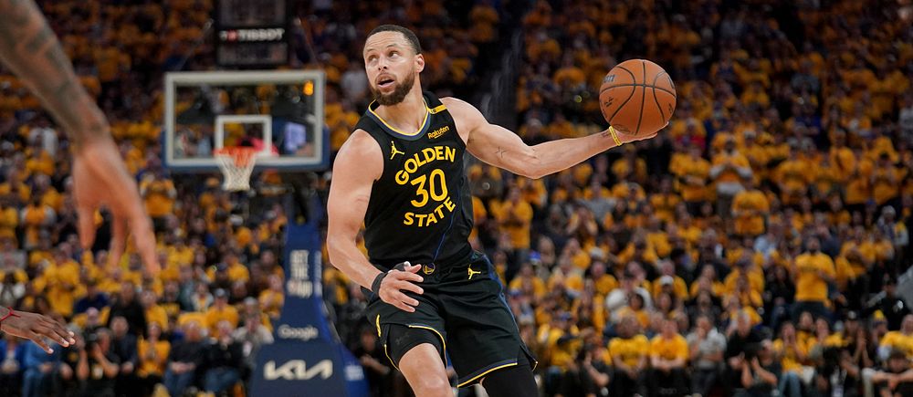 Basketspelaren Stephen Curry driver bollen under match inför publik på fullsatt arena.