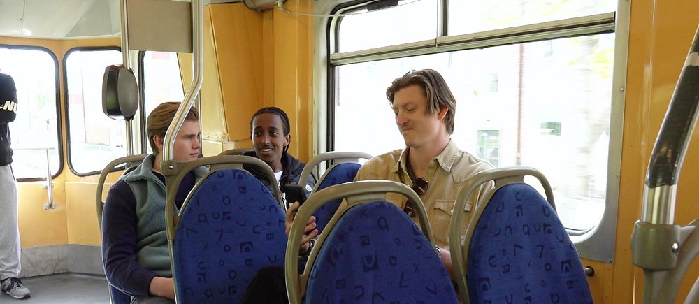 Tre personer sitter på säten i en spårvagn.