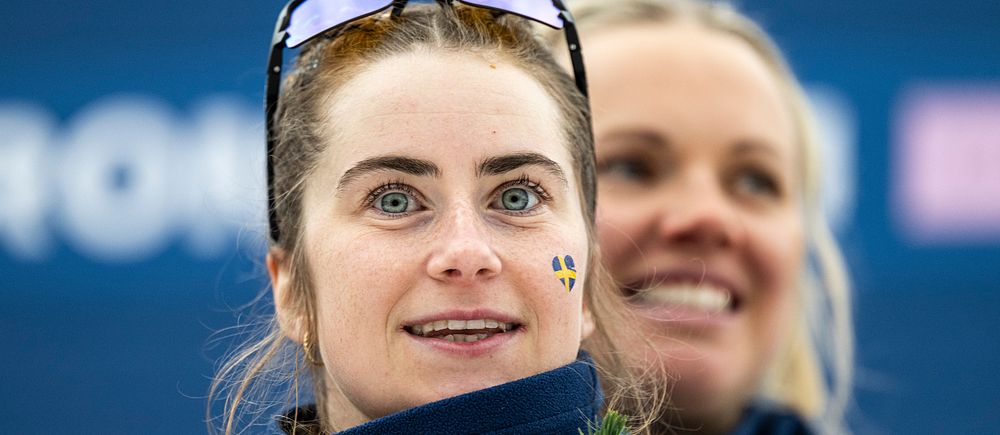 En person med sportglasögon är med i ett evenemang, omgiven av blå bakgrund med text.
