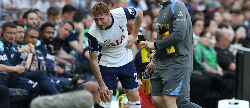 En Tottenhamspelare håller sig för höften och får hjälp vid sidlinjen under en match.