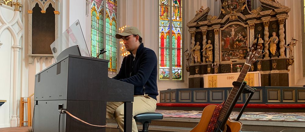 Före detta idoldeltagaren Luka Nemorin sitter vid ett piano och spelar i en kyrka i Kristinehamn