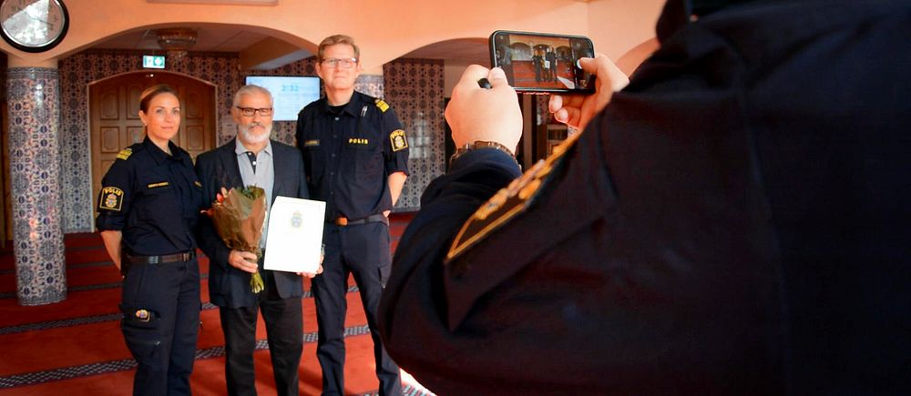 Polisen tar en bild tillsammans med Fittja Moskéns ordförande Ismail Okur. I handen har han diplomet som tack för samarbetet den 15 september 2023.