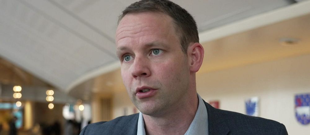 Reporter håller SVT-mikrofon i ett offentligt utrymme. Logotypen för Rapport syns.