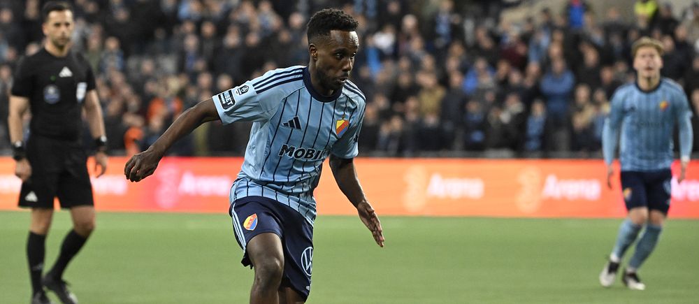 Fotbollsspelare i Djurgårdens IF driver bollen under match på fullsatt arena.