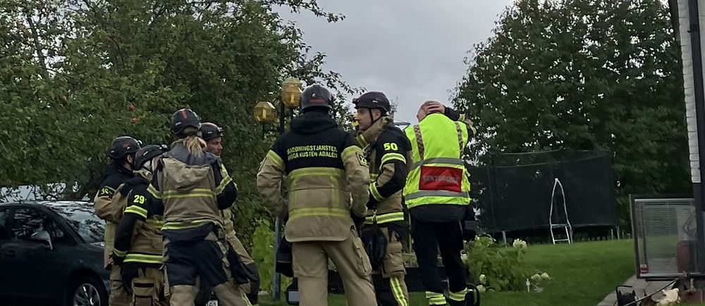 Flera personer ur räddningstjänsten står i en klunga vid en villa.