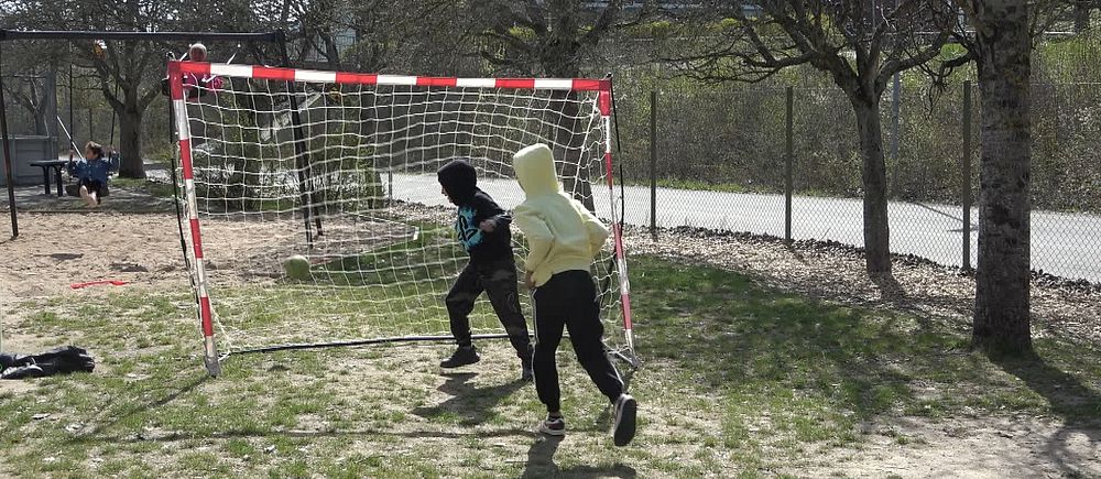 två anonyma barn tränar handboll utomhus