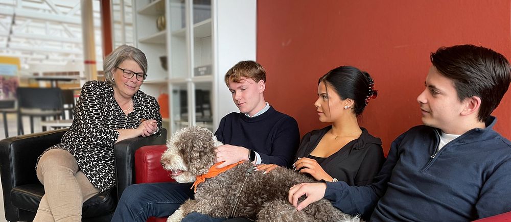Hunden Malte sitter med kuratorn Petra Birgersson och tre elever på Akademi Båstads Gymnasium.