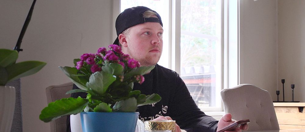 Anton Svedberg sitter vid köksbordet i Östersund och scrollar i mobilen