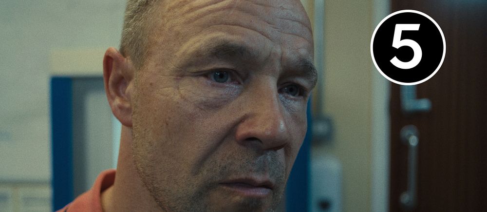 Närbild av en person i rosa skjorta med en oskarp bakgrund.
