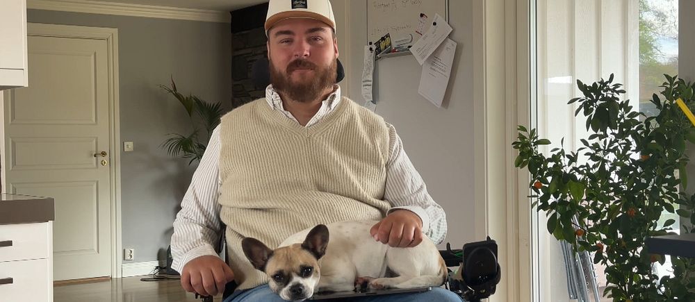 Jonathan Erikson Torell sitter i sin rullstol med en hund i knäet