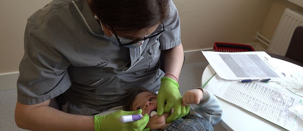 Tandsköterska undersöker en bebis tänder