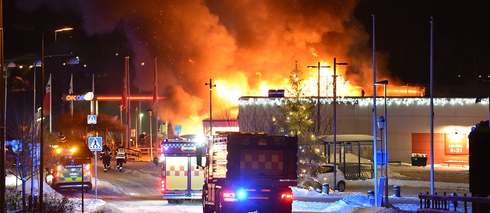 Flera brandbilar vid kraftiga brand på Ica Supermarket i Vagnhärad där lågor syns slå upp mot himlen, natten mot lördag